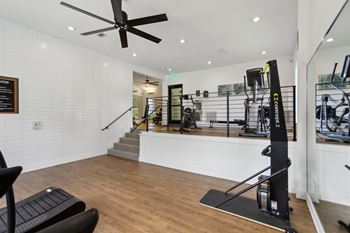 A gym with a variety of equipment including a squat rack and a bench.